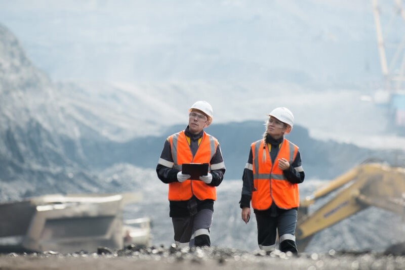 Two people wearing safety PPE walking at a mine