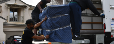 Movers loading wrapped furniture into moving truck