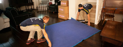 Movers laying out moving blanket next to moving boxes