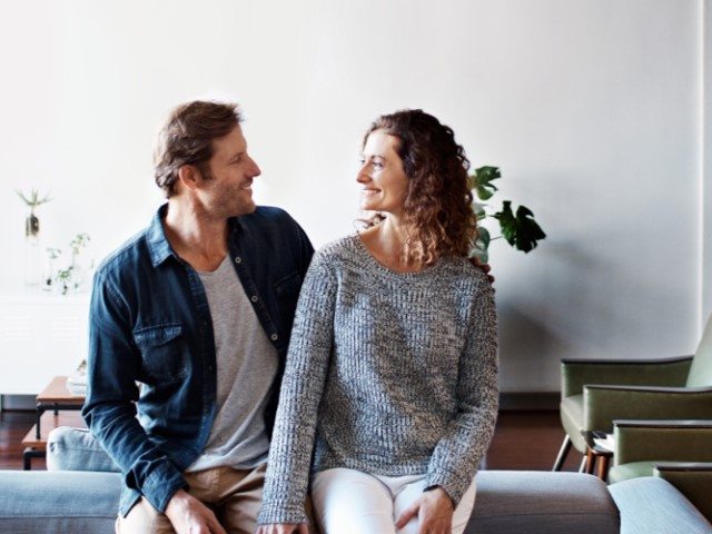 Man and woman sitting on a couch smiling at each other